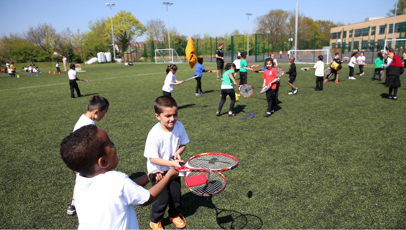 A whole class taking part in a racket and target game on the multi-use games area